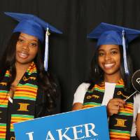 two friends with lots of props and graduation caps at GradFest